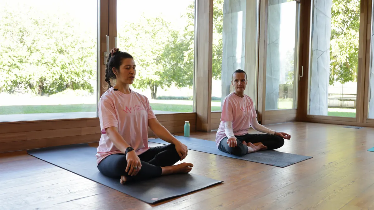 Due partecipanti in meditazione davanti alla vetrata, edizione 2023